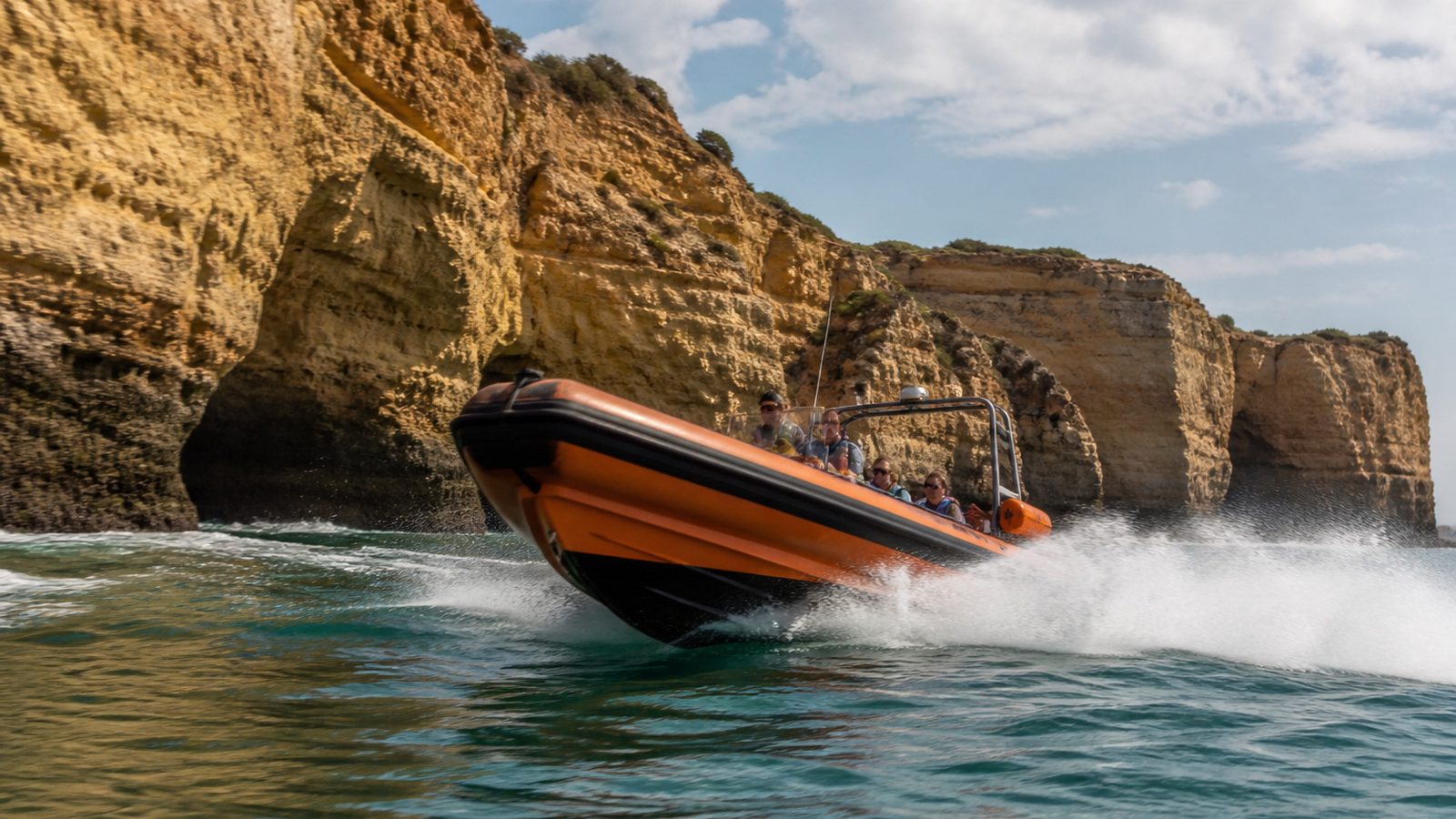 RIB running along Algarve limestone cliffs